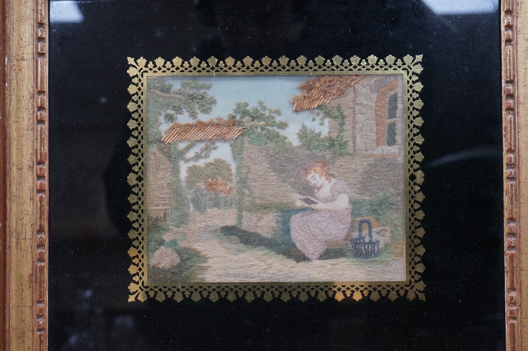 Two early 19th century silk worked embroideries one of two children with a cat, the other of a seated lady reading. Both within Verre Eglomise glass and framed. Largest 32cm x 24cm.